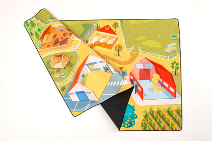 The Farmer," a vibrant play mat from Habitat Mat, is made of durable neoprene and partially rolled up to reveal barns, a haystack, fenced areas, and crop fields. Its bright colors illustrate various farm activities and structures, providing an engaging scene for imaginative play.